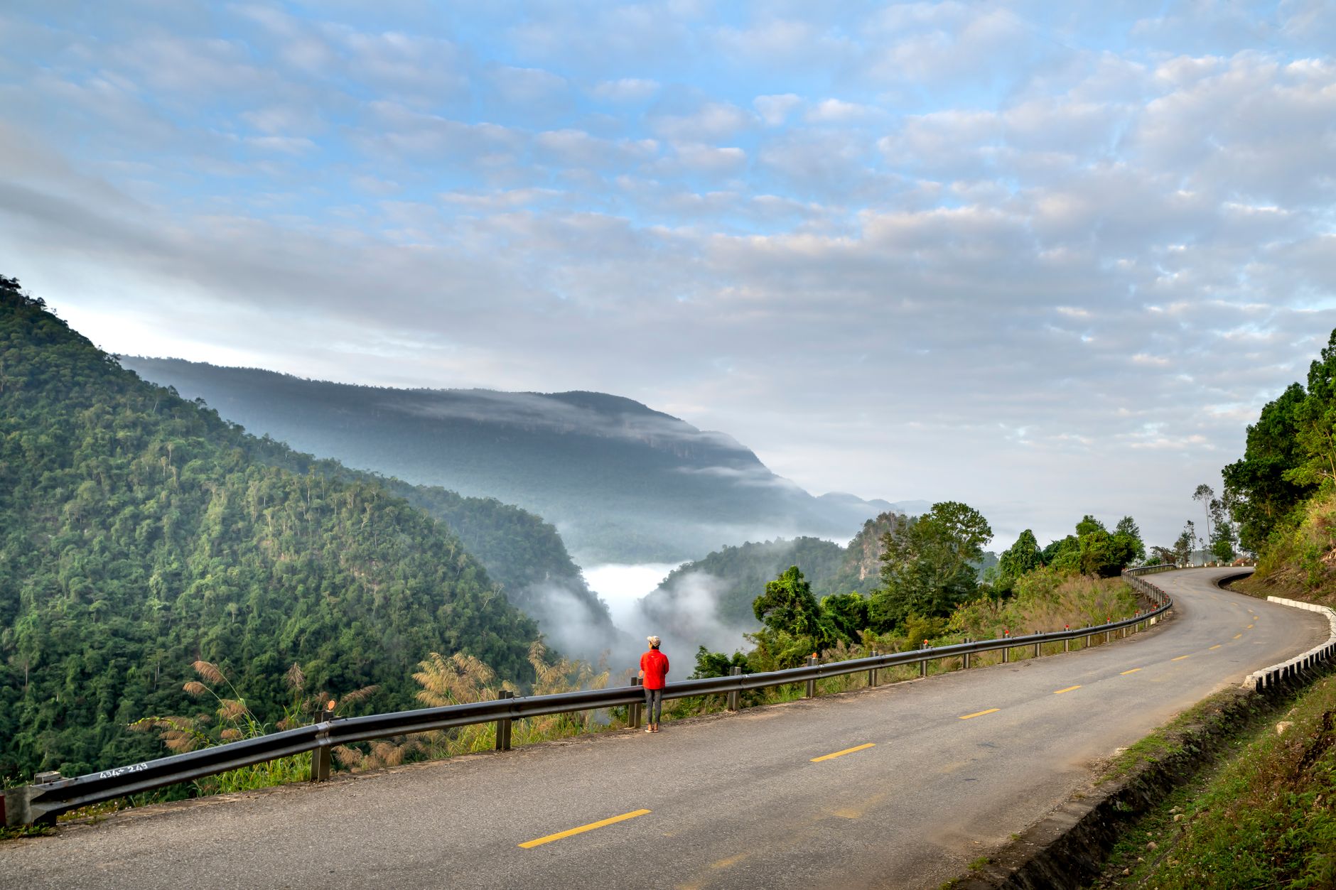 Contemplative traveler looking over misty mountains